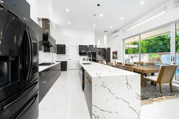 a large kitchen with stainless steel appliances kitchen island granite countertop a large counter top a stove and a refrigerator