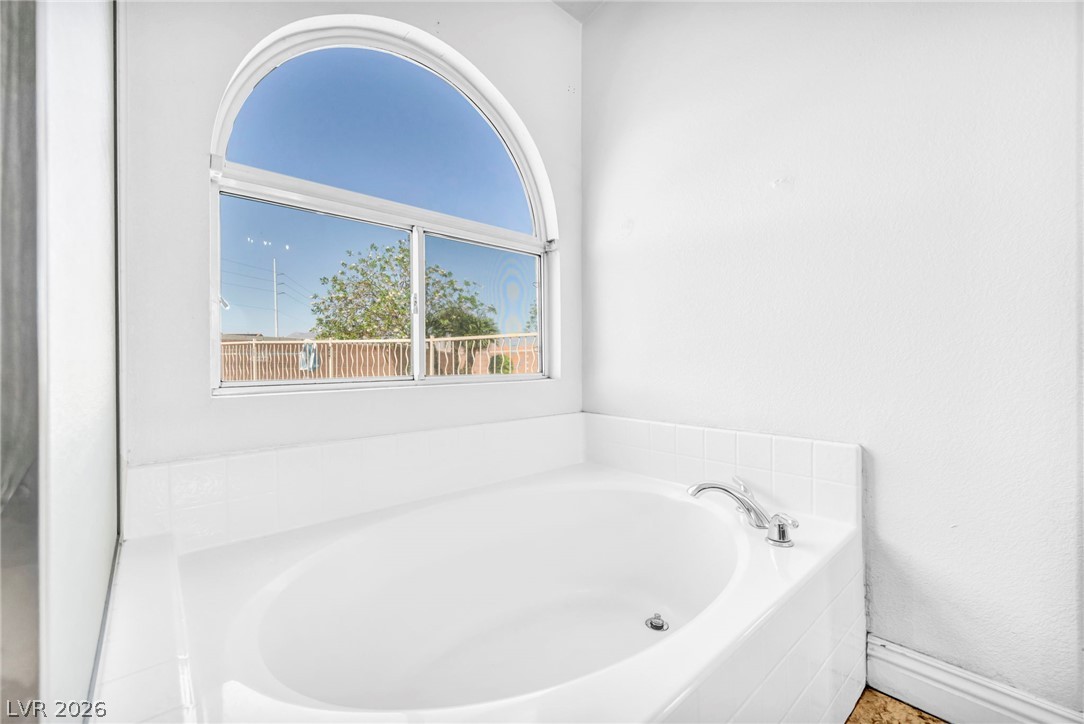 6405 North Raptor Court North Las Vegas, NV 89084 - Photo 36 of 66 Indulge in relaxation within this primary bathroom featuring a spacious soaking tub beneath an arched window.