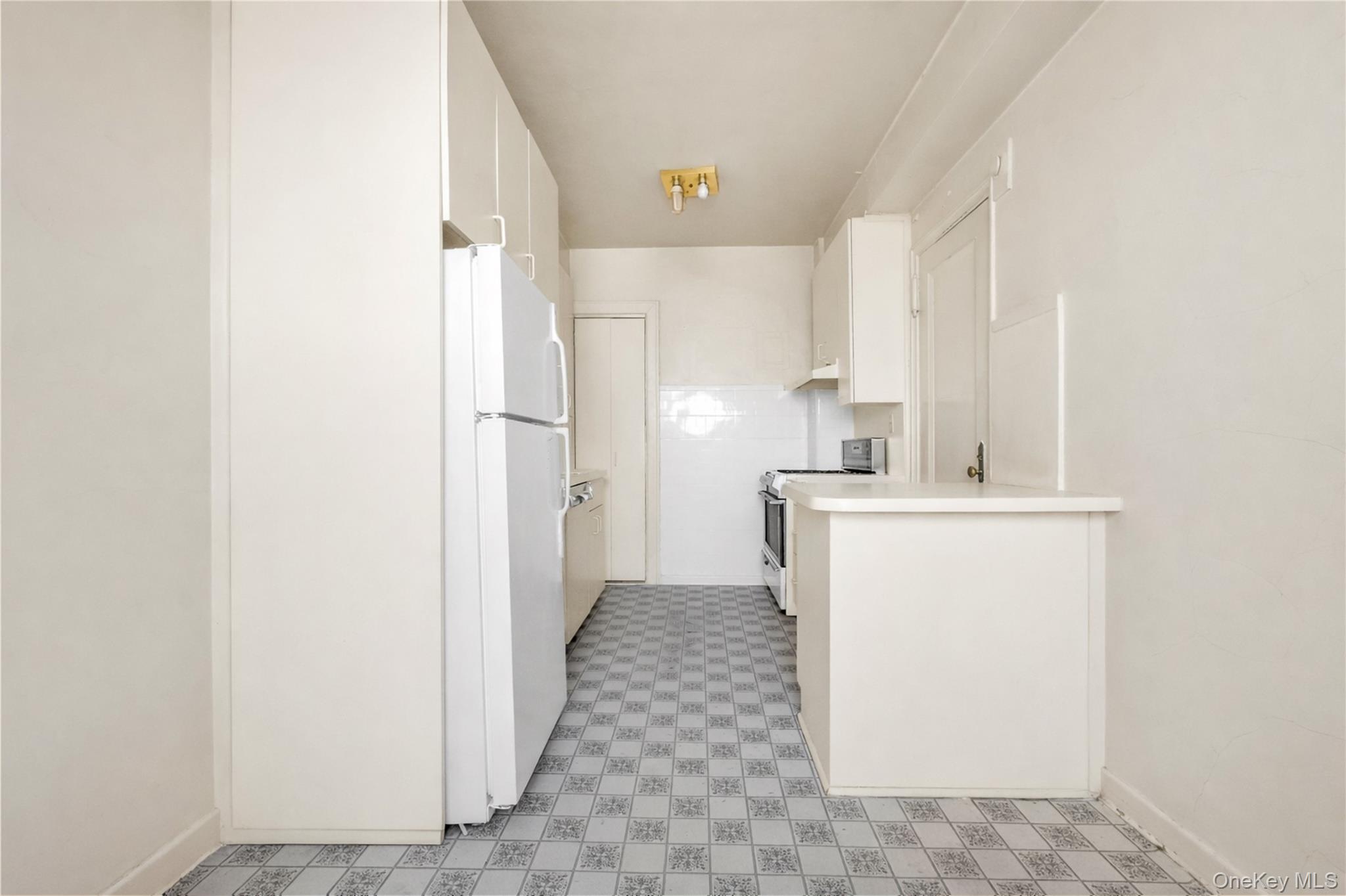 390 Riverside Drive, Unit 15D Manhattan, NY 10025 - Photo 5 of 29 Kitchen with light floors, freestanding refrigerator, white cabinetry, electric range, and light countertops
