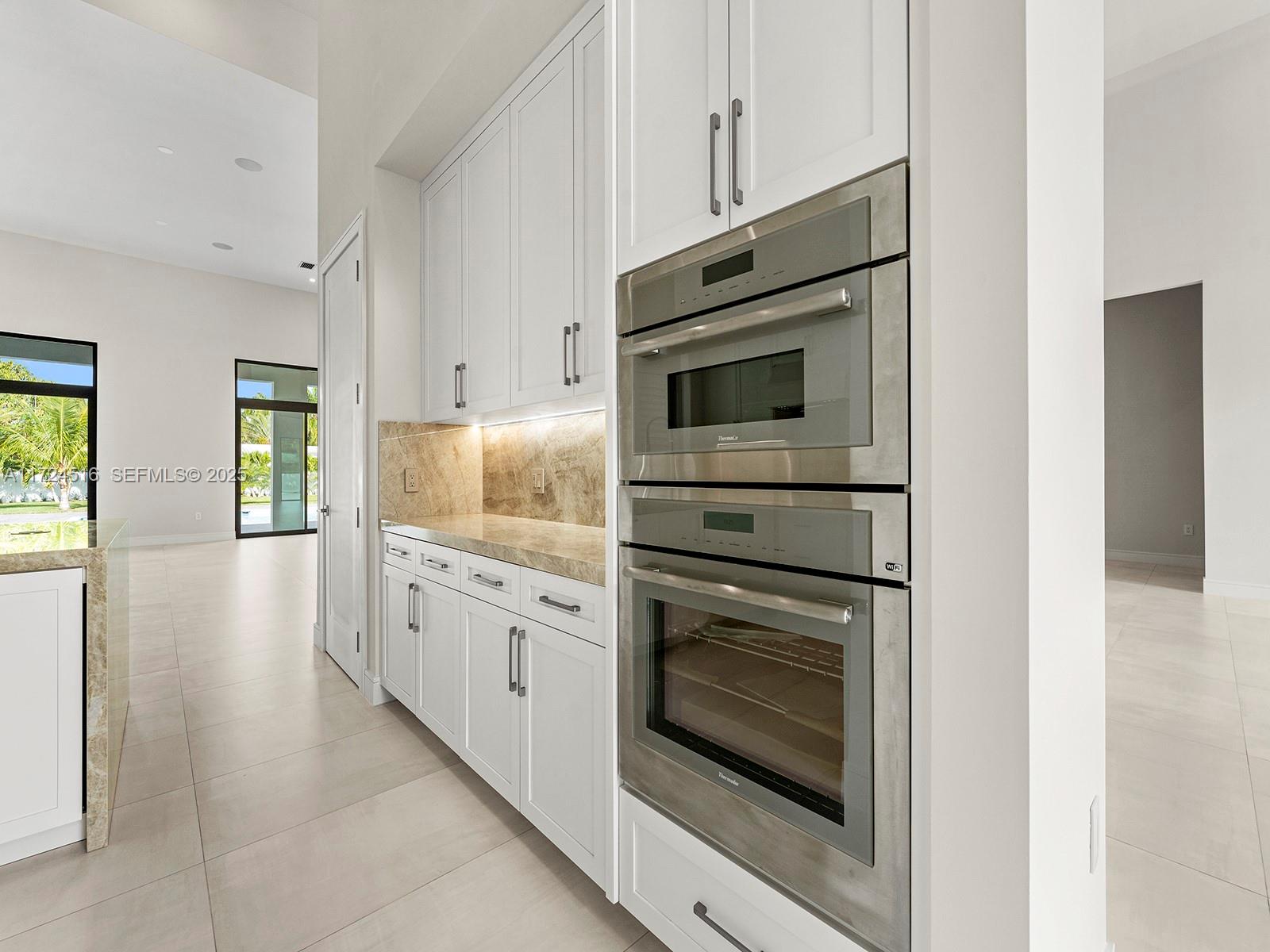 12025 Southwest 46th Street Miami, FL 33175 - Photo 9 of 45 a kitchen with white cabinets and stainless steel appliances
