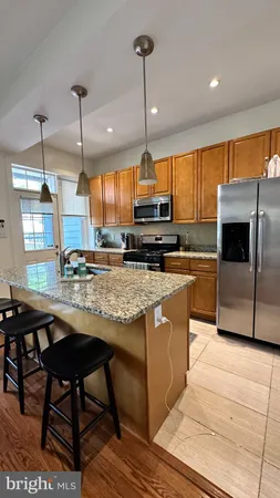 a kitchen with stainless steel appliances kitchen island granite countertop a table chairs and a wooden cabinets