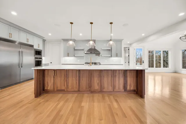 a large kitchen with granite countertop a large counter top stainless steel appliances and cabinets