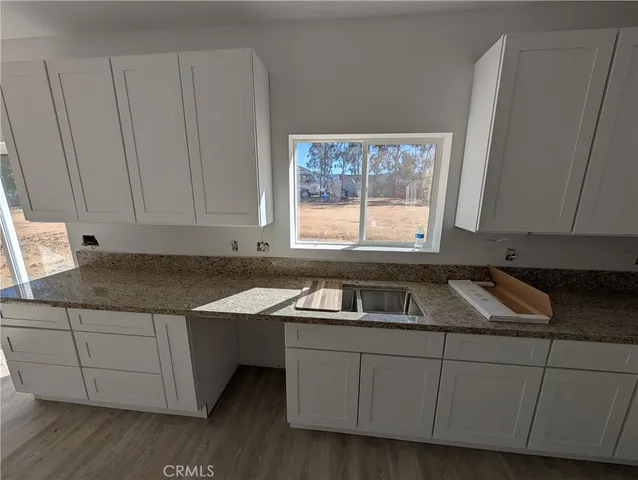 a kitchen with stainless steel appliances white cabinets and wooden floor