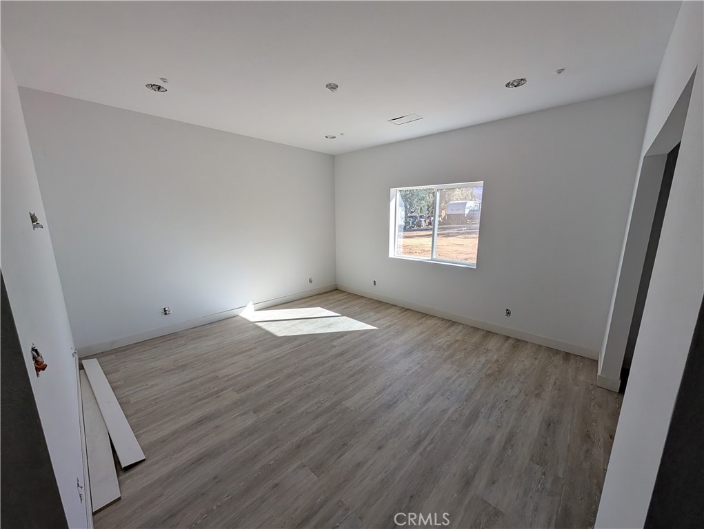 43145 Bob Cat Road Banning, CA 92220 - Photo 26 of 49 an empty room with wooden floor and windows