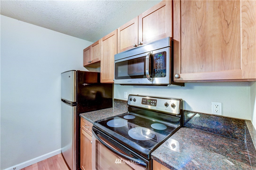 10831 Northeast 147th Lane, Unit R103 Bothell, WA 98011 - Photo 11 of 15 a kitchen with stainless steel appliances granite countertop a stove microwave and sink