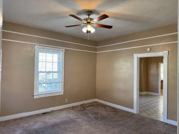 a view of an empty room with a ceiling fan and window