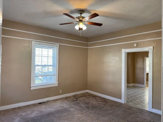 a view of an empty room with a ceiling fan and window