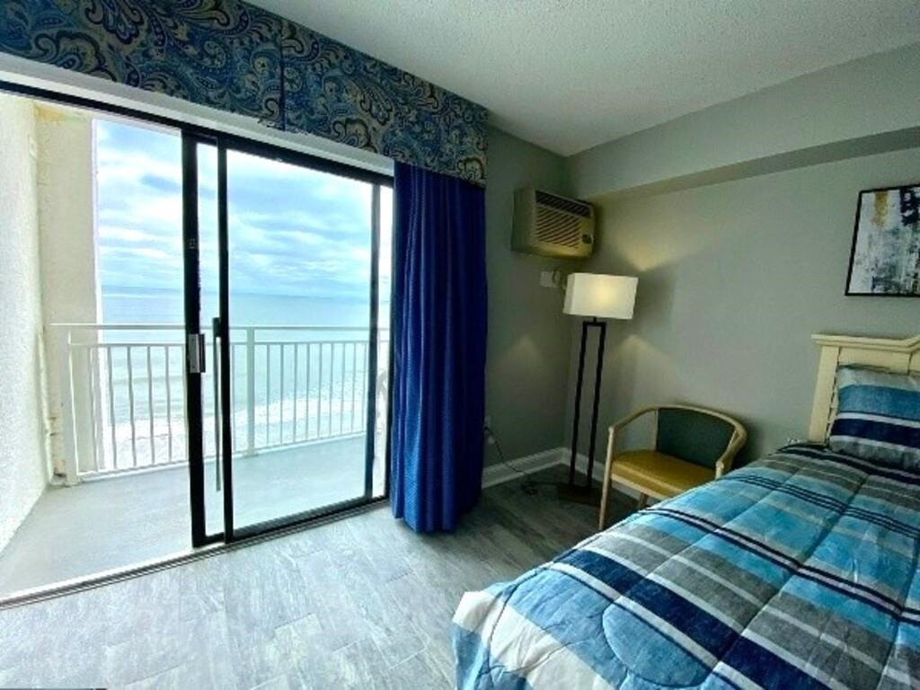 1207 South Ocean Boulevard, Unit 20809 Myrtle Beach, SC 29577 - Photo 9 of 19 Bedroom with an AC wall unit, wood-type flooring, access to outside, a water view, and a textured ceiling