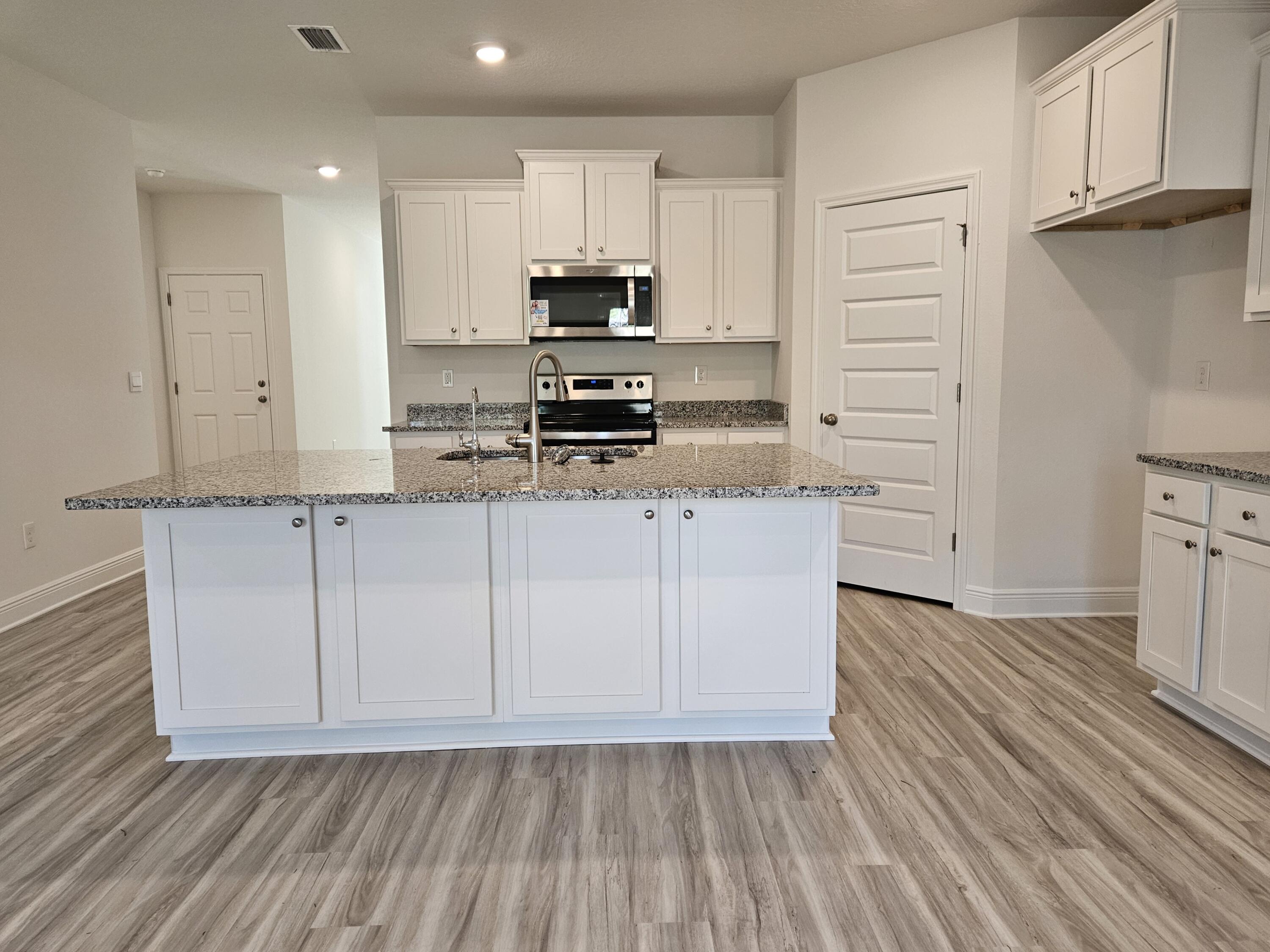 7 Nest Lane Santa Rosa Beach, FL 32459 - Photo 5 of 16 a kitchen with granite countertop white cabinets and stainless steel appliances
