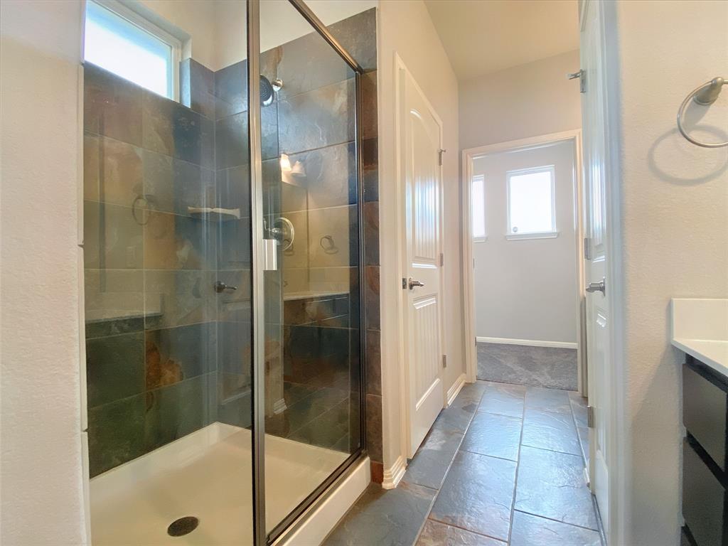 8901 Panhandle Drive Austin, TX 78747 - Photo 13 of 21 Walk-in shower with natural stone tile surround, glass enclosure, and a built-in shelf