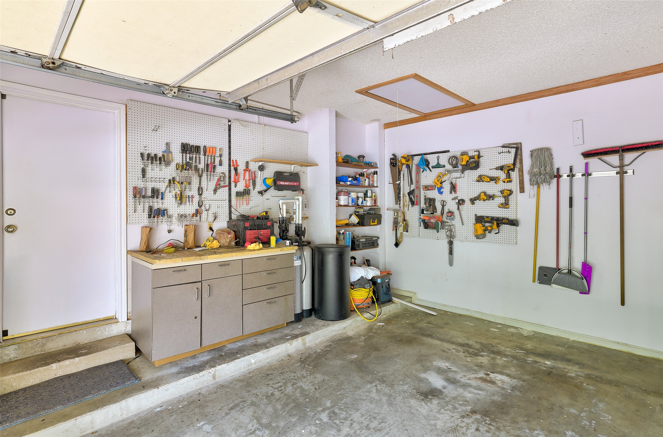 110 South Ridge Circle Georgetown, TX 78628 - Photo 29 of 37 Garage workshop featuring extensive pegboard organization, a built-in workbench with cabinet storage, and concrete flooring