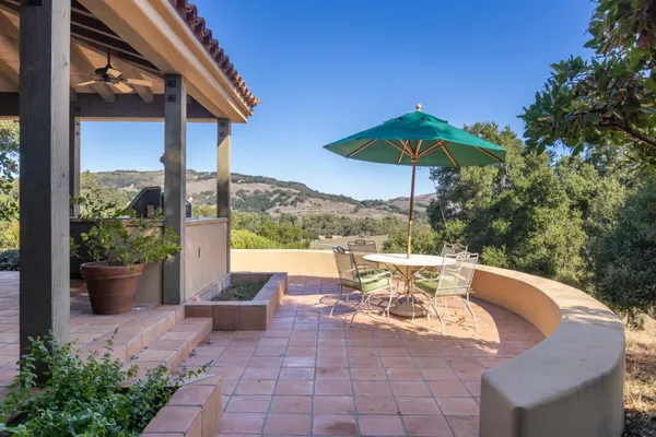 a view of a patio with couches table and chairs under an umbrella