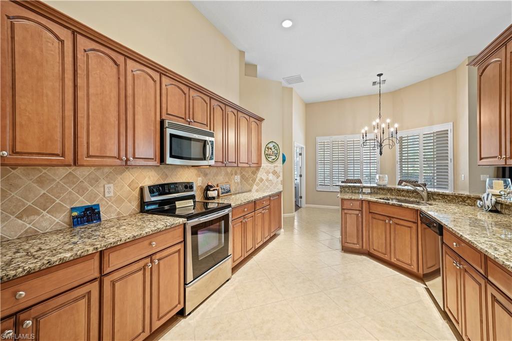7950 Founders Circle Naples, FL 34104 - Photo 6 of 43 a kitchen with stainless steel appliances granite countertop a stove a sink dishwasher and a microwave oven with white cabinets