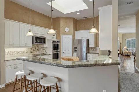 a kitchen with granite countertop a sink cabinets and stainless steel appliances