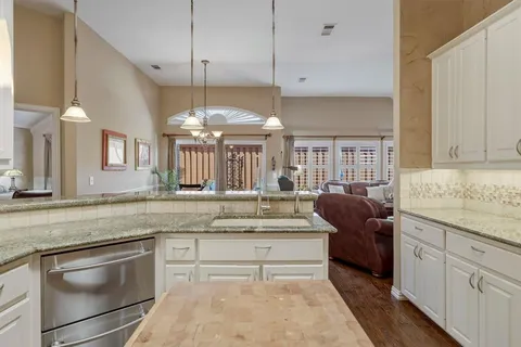 a kitchen with granite countertop a stove and white cabinets