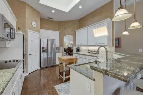 a kitchen with stainless steel appliances granite countertop a sink refrigerator and cabinets