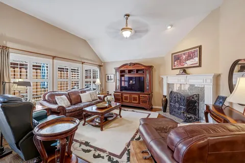 a living room with furniture a fireplace and large windows