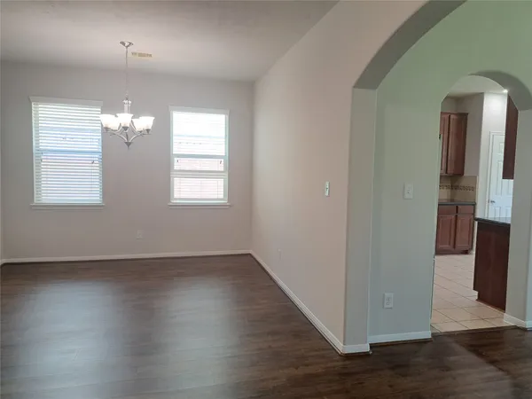 an empty room with wooden floor chandelier and windows