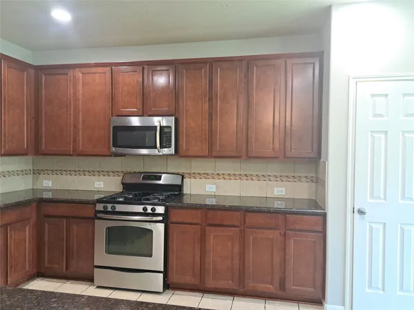 a kitchen with granite countertop stainless steel appliances wooden cabinets and a stove top oven