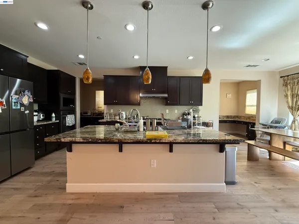 a kitchen with stainless steel appliances granite countertop wooden floors a stove and a sink