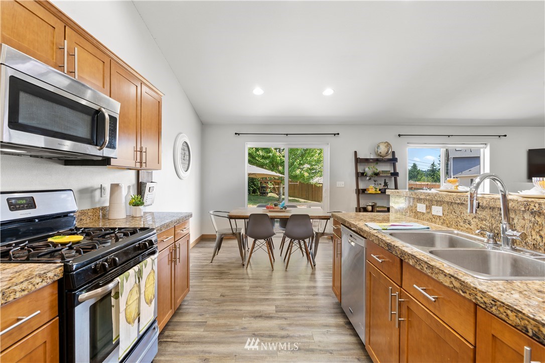 20815 9th Drive Southeast Bothell, WA 98021 - Photo 6 of 23 a kitchen with stainless steel appliances granite countertop a stove top oven a sink dishwasher a dining table and chairs with wooden floor