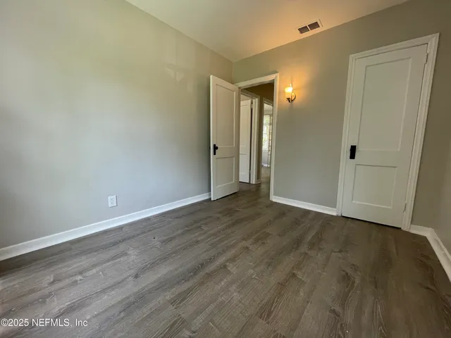 a view of an empty room with wooden floor and closet