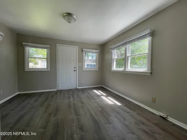 an empty room with wooden floor and windows