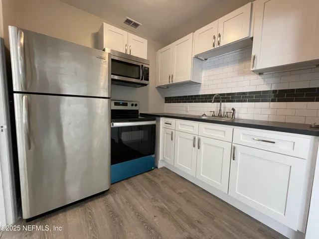 a kitchen with stainless steel appliances granite countertop a refrigerator a sink a stove a microwave and cabinets