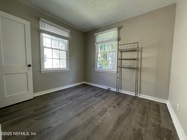 an empty room with wooden floor and window