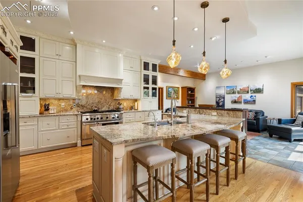 a kitchen with stainless steel appliances granite countertop a stove a sink a oven a kitchen island with white cabinets and wooden floor