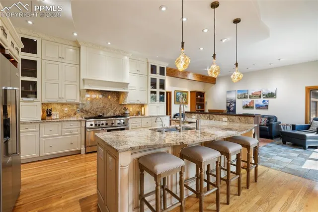 a kitchen with stainless steel appliances granite countertop a stove a sink a oven a kitchen island with white cabinets and wooden floor