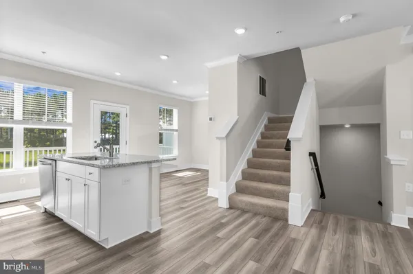 a kitchen with kitchen island granite countertop a sink cabinets and wooden floor