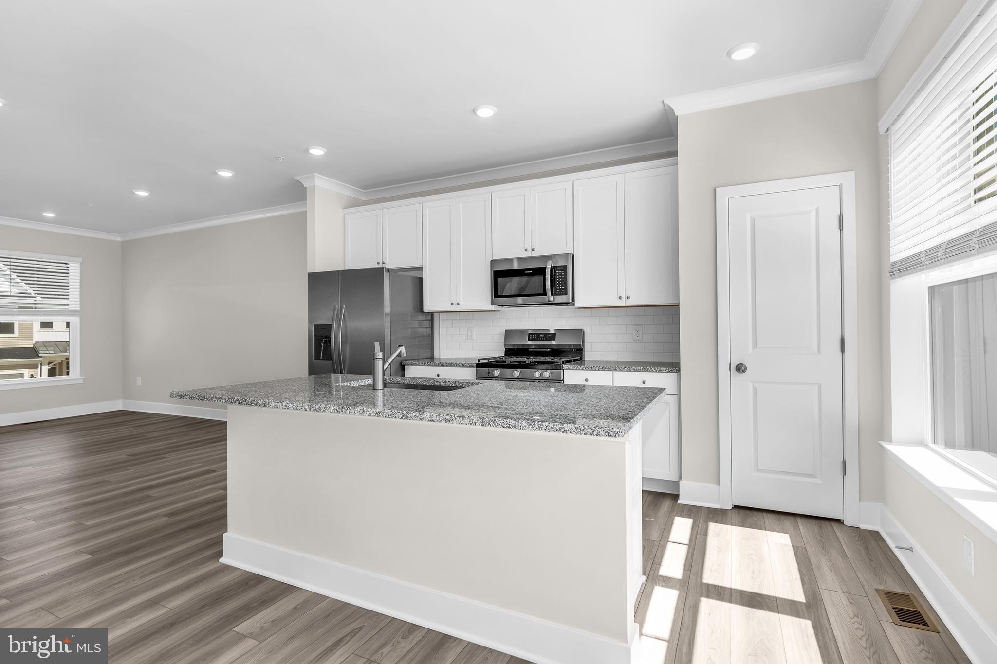 2110 Winterberry Lane Cambridge, MD 21613 - Photo 13 of 46 a kitchen with kitchen island granite countertop a sink cabinets and wooden floor