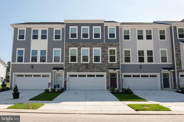 a front view of a building with a garden and garage