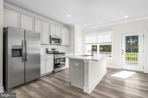a kitchen with stainless steel appliances a microwave a sink a stove a refrigerator and cabinets