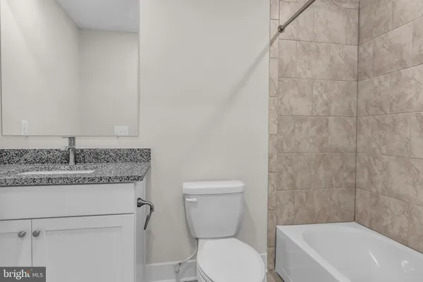 a bathroom with a granite countertop toilet a sink and bathtub