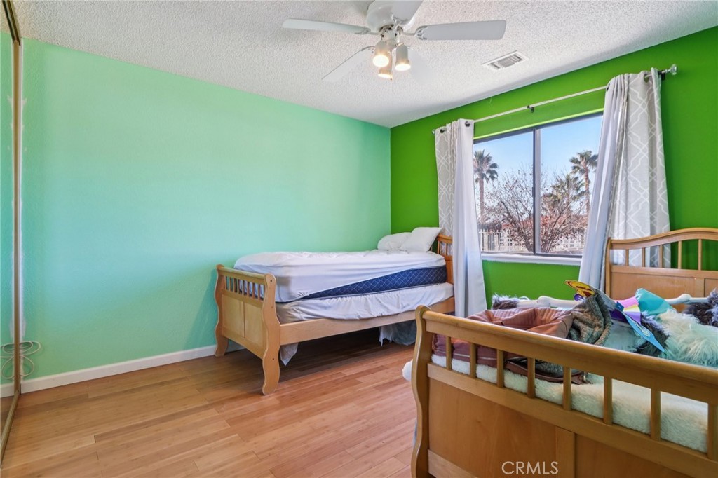 14057 Crow Road Apple Valley, CA 92307 - Photo 18 of 33 a room with wooden floors bed and fan