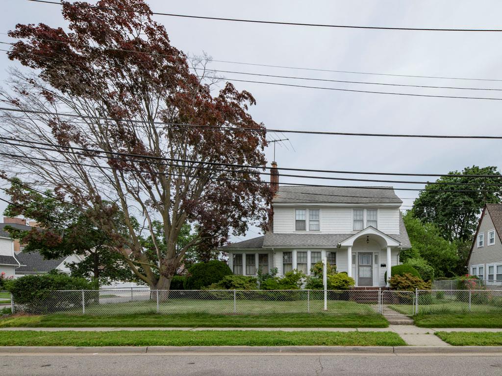 a view of a white house with a big yard and potted plants
