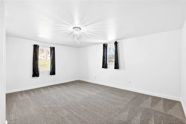 an empty room with ceiling fan and windows