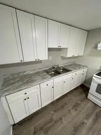 a kitchen with granite countertop white cabinets and white appliances