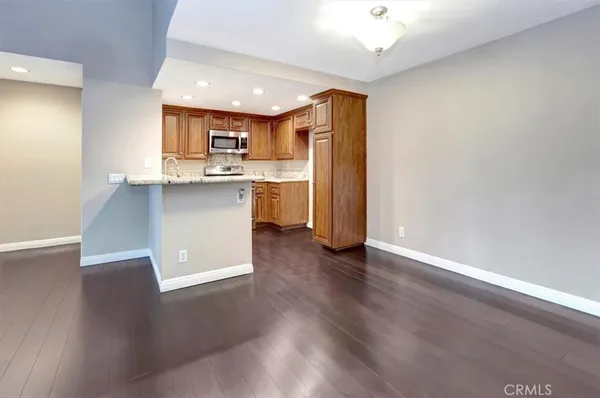 a kitchen with stainless steel appliances granite countertop a refrigerator a sink dishwasher and a oven with wooden floor