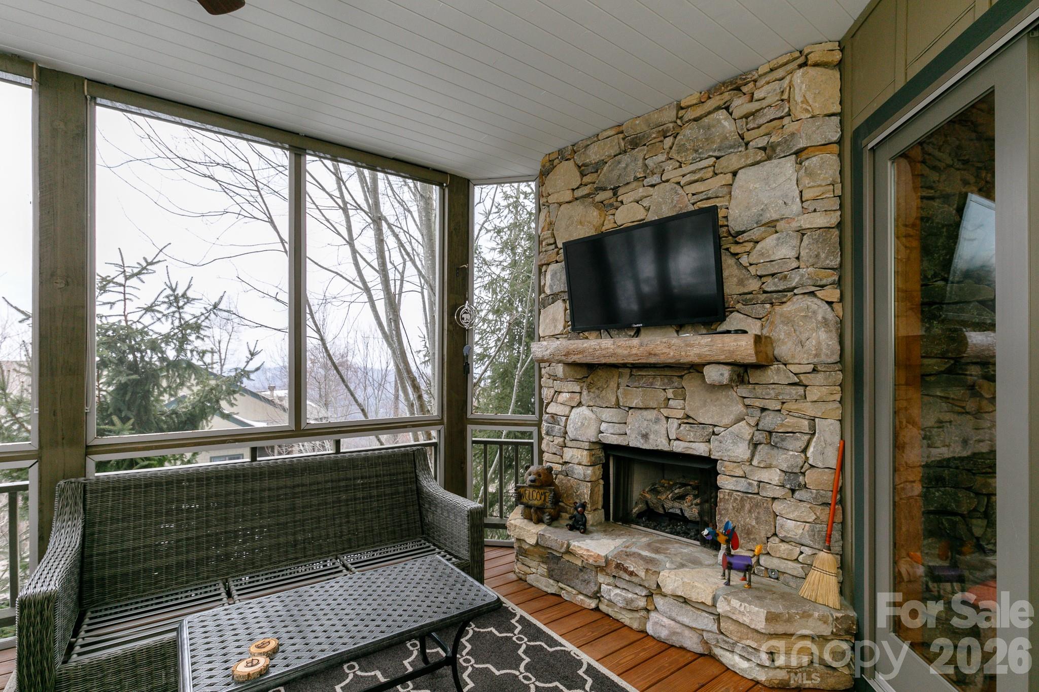 528 Andrew Banks Road, Unit A/3 Burnsville, NC 28714 - Photo 20 of 30 a living room with a fireplace a flat screen tv and a floor to ceiling window