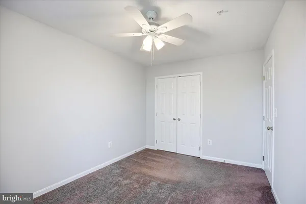 an empty room with a chandelier fan and windows