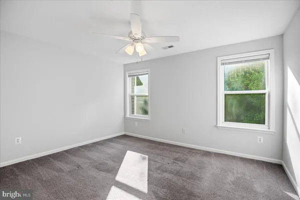 an empty room with windows and fan