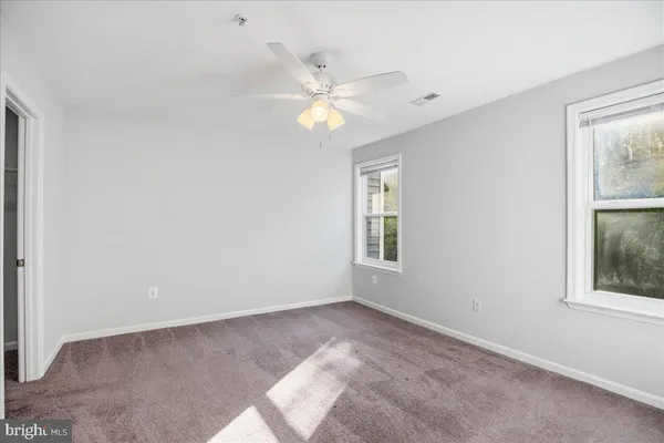 a view of an empty room with window and chandelier fan