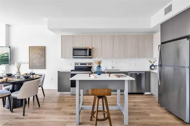 a kitchen with stainless steel appliances a stove a sink a refrigerator a dining table and chairs