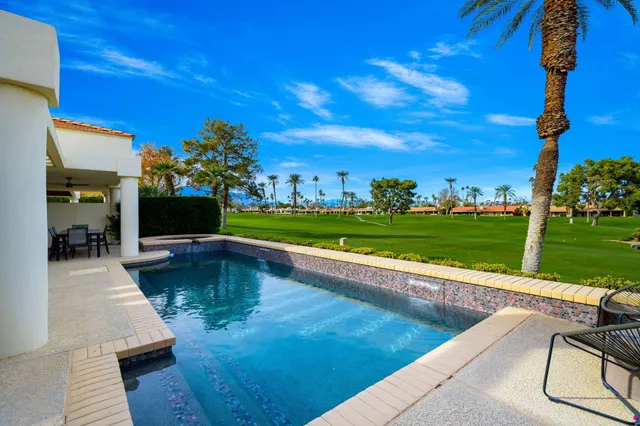 a view of a swimming pool and lounge chairs in back yard of the house