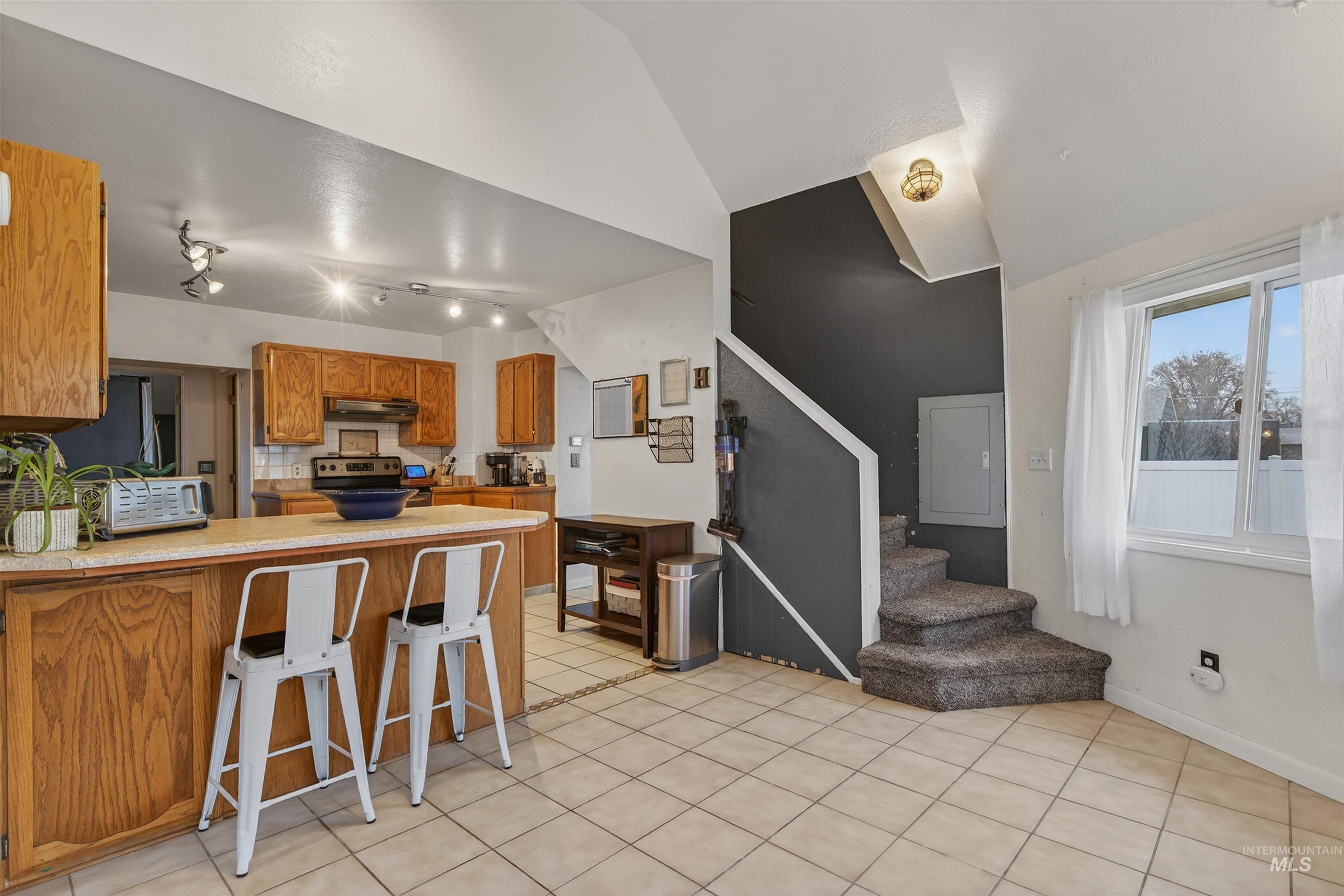 1266 Poplar Street Clarkston, WA 99403 - Photo 11 of 31 Kitchen with a peninsula, wood finish cabinets, a breakfast bar area, stainless steel appliances, and light tile patterned floors