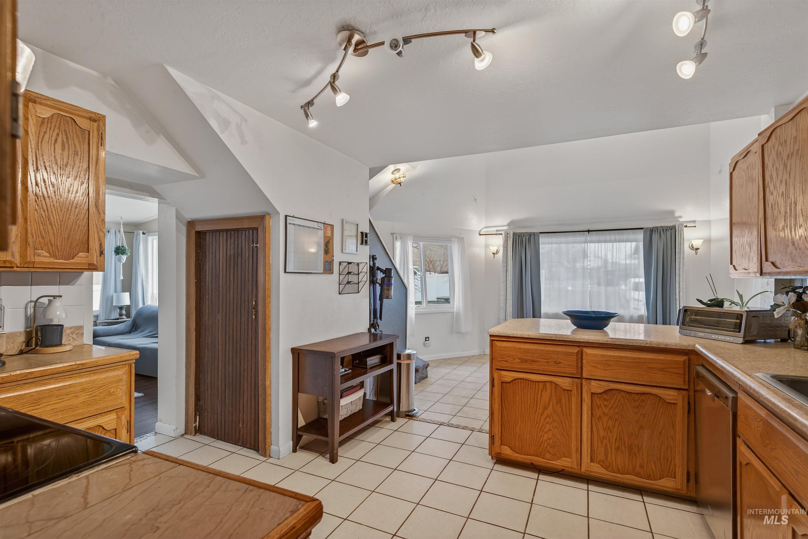 1266 Poplar Street Clarkston, WA 99403 - Photo 12 of 31 Kitchen with light countertops, wood finish cabinetry, vaulted ceiling, a peninsula, and light tile patterned floors