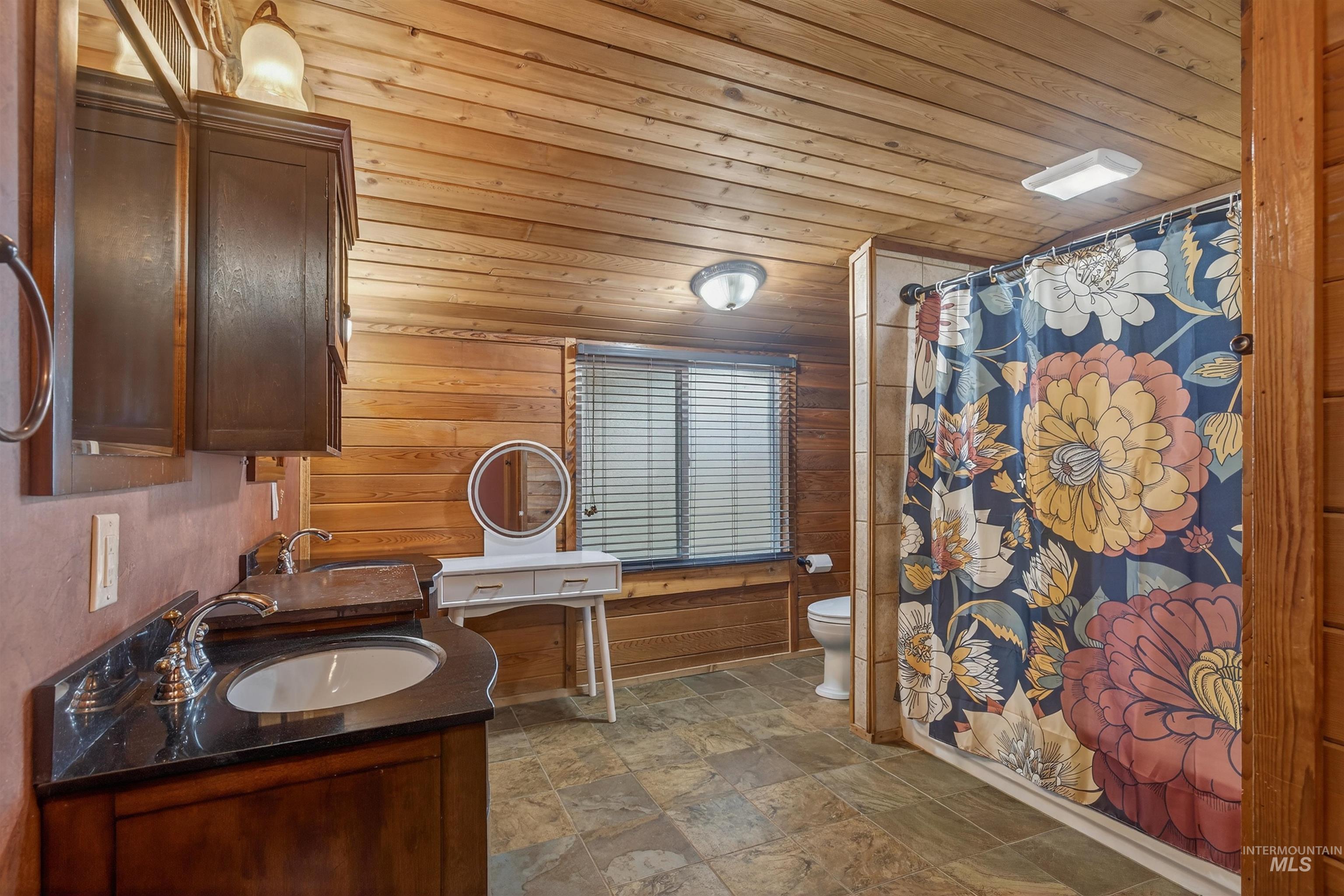 1266 Poplar Street Clarkston, WA 99403 - Photo 18 of 31 Full bath with stone finish flooring, wood walls, double vanity, shower / bath combo with shower curtain, and wood ceiling
